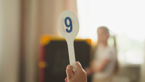 el escolar levanta la etiqueta con el dígito nueve y la niña resuelve las tareas