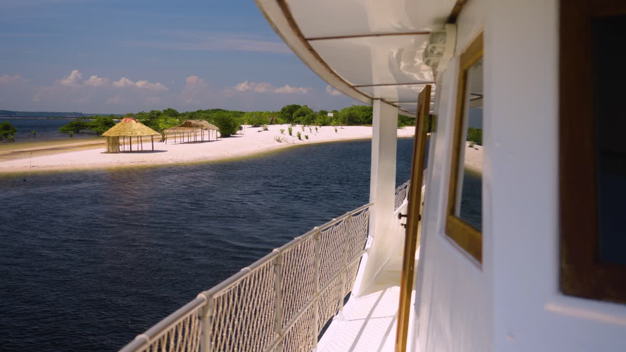 Eine Yacht fährt an einer unberührten tropischen Insel mit einem weißen Sandstrand vorbei. Zeitlupe