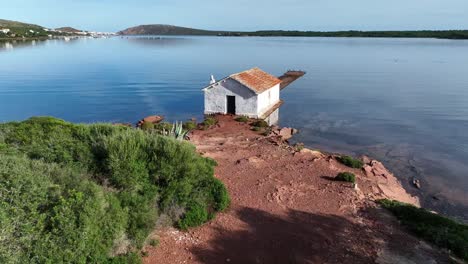 Alter-Bootsschuppen-Am-Ufer-Der-Bucht-Von-Fornells-Auf-Menorca,-Spanien,-Mit-Belebtem-Pier-Und-Vögeln,-Die-Ihr-Zuhause-Beanspruchen