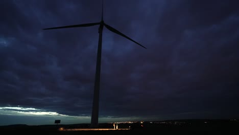 massive storm clouds over big wind turbine producing electricity, time-lapse