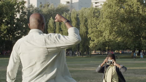 black man showing biceps while his young son taking photo.