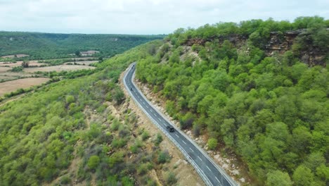 Vista-Aérea-De-Drones-De-Un-Coche-Y-Una-Motocicleta-Conduciendo-Por-Una-Carretera-Rural-Curva-En-Las-Colinas