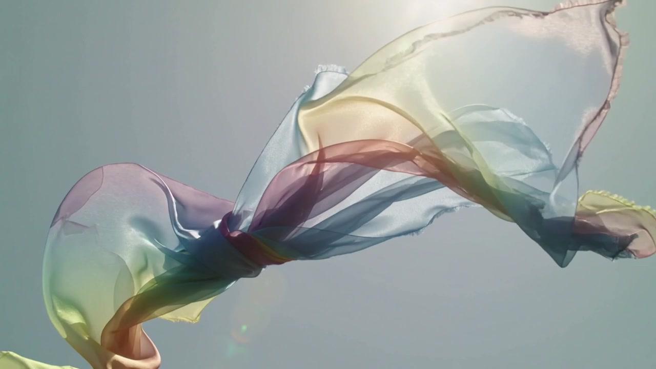 Billowing sheer multicolor scarf, central knot twisting over blue sky, sun flare, driven by wind
