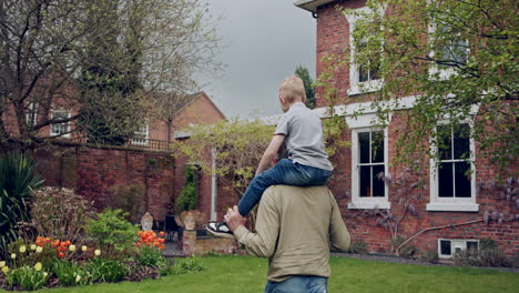 grandfather carrying grandson on his shoulders in the yard