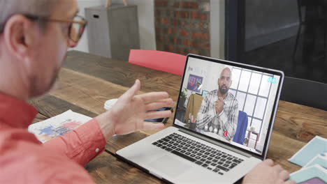 hombre de negocios caucásico en una llamada de video portátil con un colega afroamericano en la pantalla