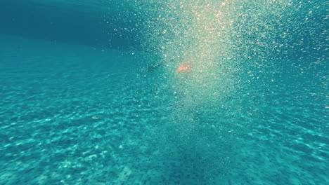 un joven nada bajo el agua en una piscina.