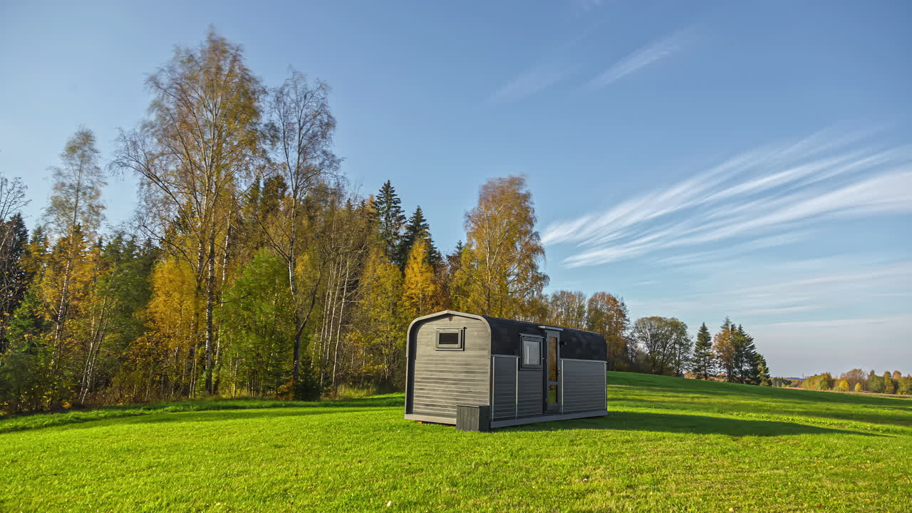 casa de madera rodeada de árboles forestales en el pasto durante el día otoñal nublado - lapso de tiempo