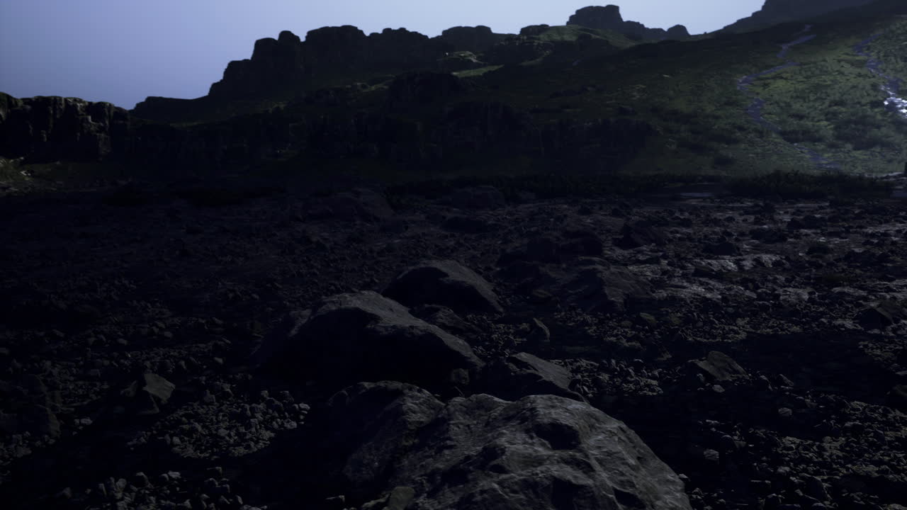 Rocky terrain under moonlight near a mountain range at nighttime