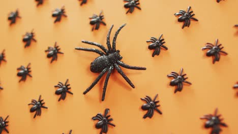 Close-up-view-of-multiple-spider-toys-against-orange-background