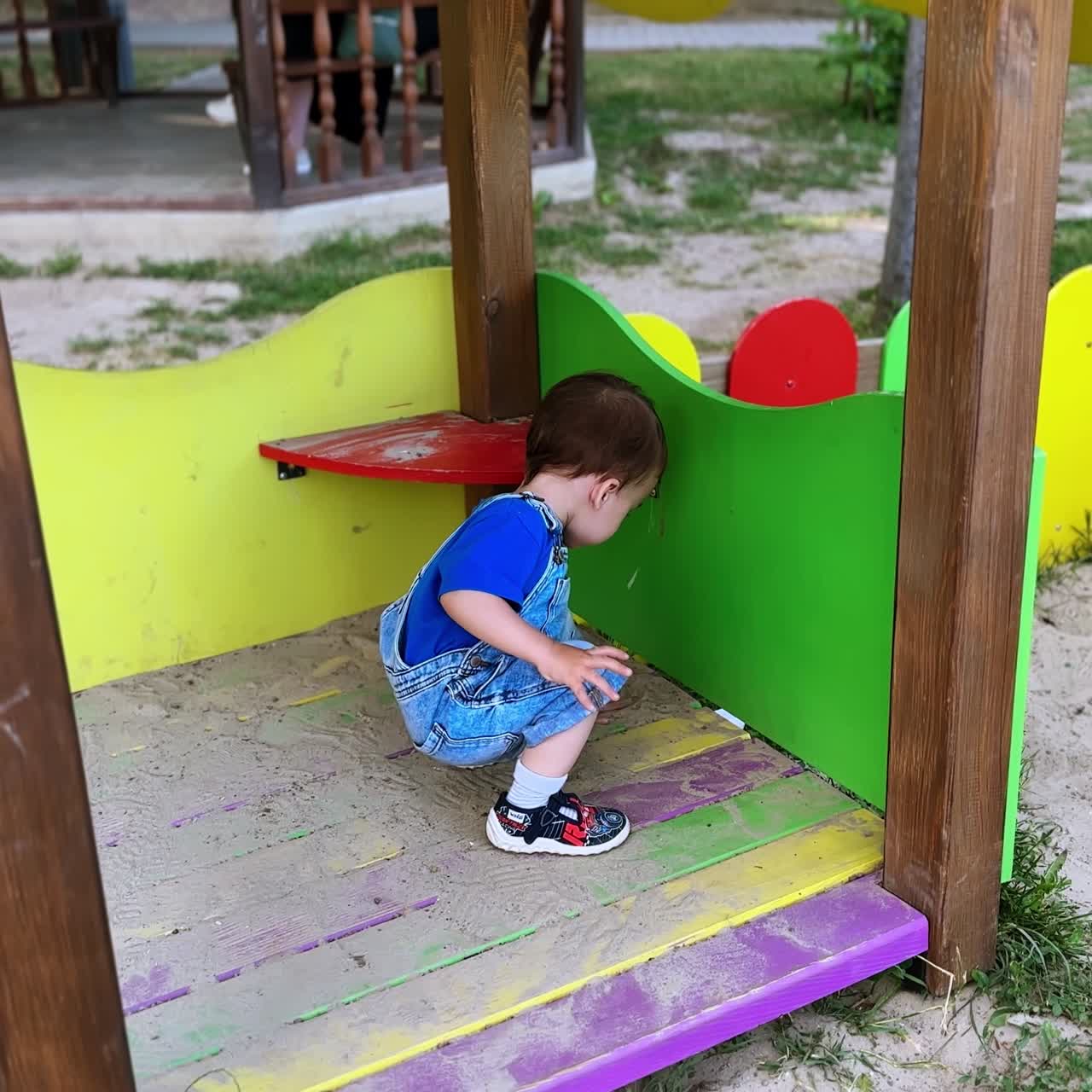 Adorable y encantador niño jugando en la casita de madera. Bebé jugando con arena en el parque infantil