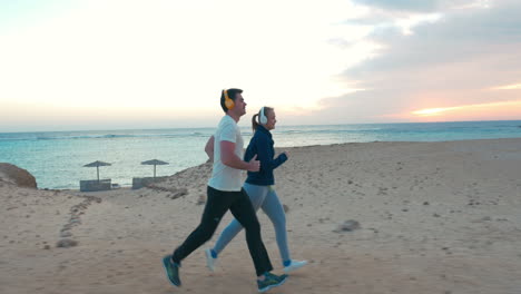 young people jogging on the beach at sunset