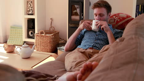 handsome young man relaxing on his couch with a hot drink