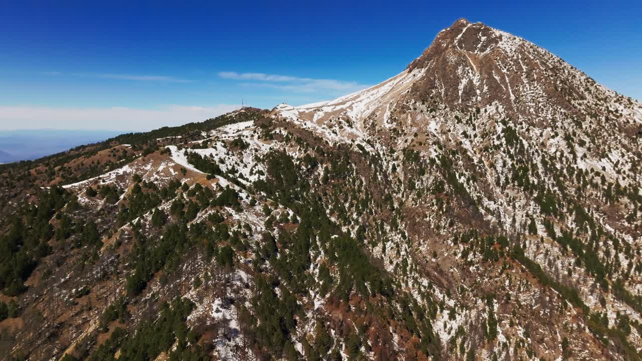 Snow-covered Nevado de Colima peak with pine forest canopy below. Pan left reveals Mirador Volcán de Fuego viewpoint.