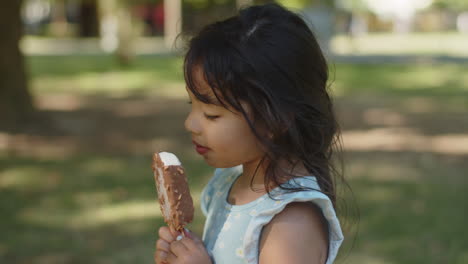 vista laterale della bambina carina che lecca il gelato al cioccolato all'aperto