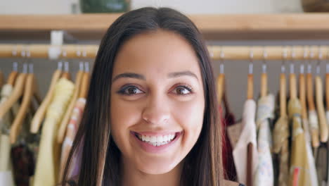 retrato de una cliente o propietaria de pie junto a estantes de ropa en una tienda de moda independiente