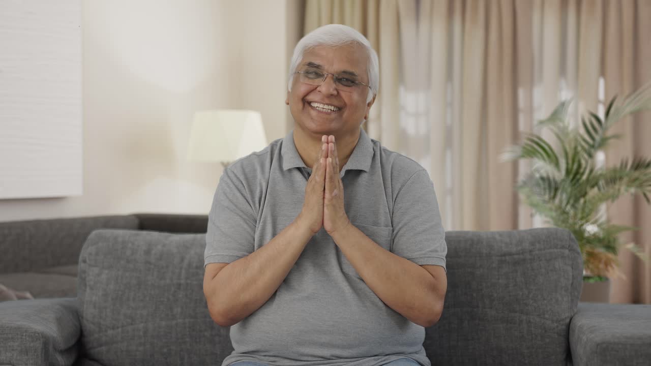 Happy Indian old man greeting and doing Namaste
