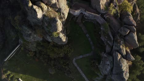 an overhead aerial drone shot moving from the bottom going up, showing the fortified walls of the belogradchik rock fortress, in the province of vidin in northwestern bulgaria