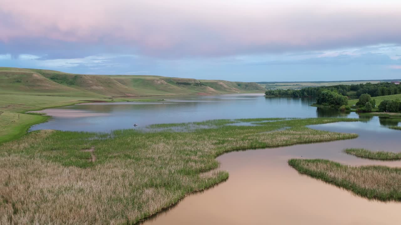 el cielo cubierto de nubes se refleja en la superficie del agua. una cálida noche de verano en la naturaleza. islotes de verdor cruzan el lago. un lugar para unas vacaciones familiares. fotografía aérea.
