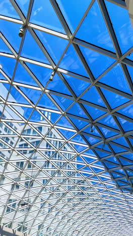 long glass roof with metal constructions. low angle view. blue sky at backdrop. vertical video.