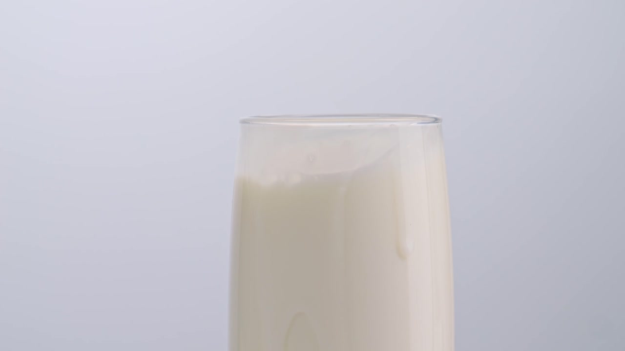 cubos de hielo cayendo en un vaso de leche sobre un fondo blanco