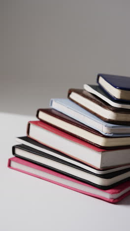 vertical video of stack of books and notebooks with copy space on grey background