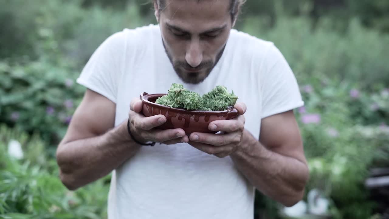 Man smelling herbs in a garden