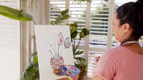 painting on canvas, woman creating artwork with palette in hand at home