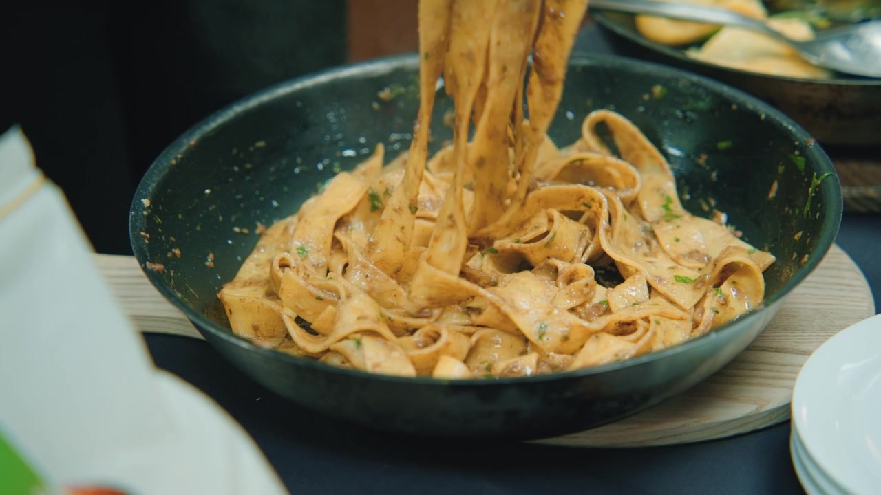 Una persona prende la pasta da una ciotola e la mette nel piatto, preparando il cibo da servire