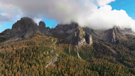 Atemberaubende-Drei-Zinnen-üppiger-Waldhang-Luftbild-über-Südtiroler-Berggipfel-Wolkengebilde