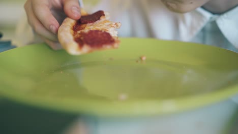 boy has dinner with tasty pizza from color plate closeup