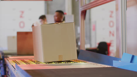 Diverse-male-and-female-workers-with-boxes-on-conveyor-belt-in-warehouse