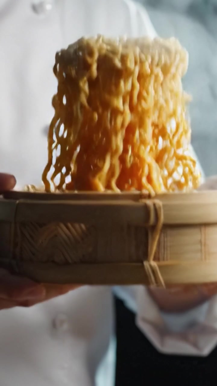 Una deliziosa porzione di noodles al vapore in un cestino di bambù, che evidenzia le abilità culinarie e l'arte della cucina asiatica con vapore che sale in una splendida cornice.