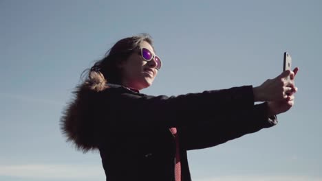 Girl-takes-selfie-and-pictures-with-the-smartphone-in-slow-motion-pan-with-sky-in-the-background