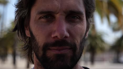 serious bearded man with long hair looking directly at camera