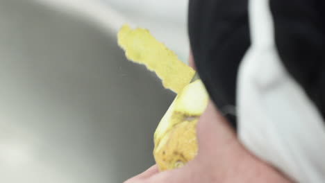 close up of hands using peeler to strip zest off a lemon