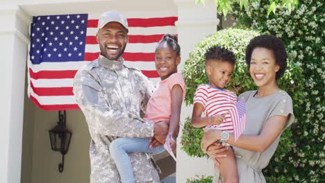 happy african american male soldier and wife holding daughter and son outside home, slow motion