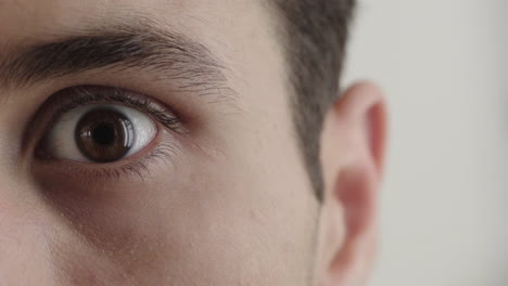 close up young hispanic man opening eye looking surprised shocked white background