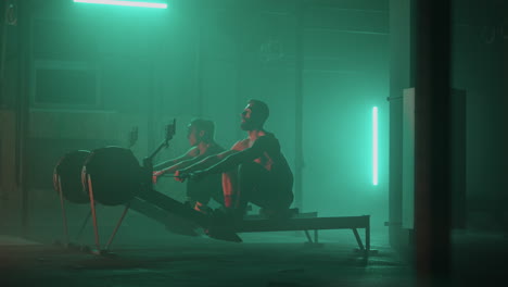 slow motion: man and woman training on a rowing machine in gym