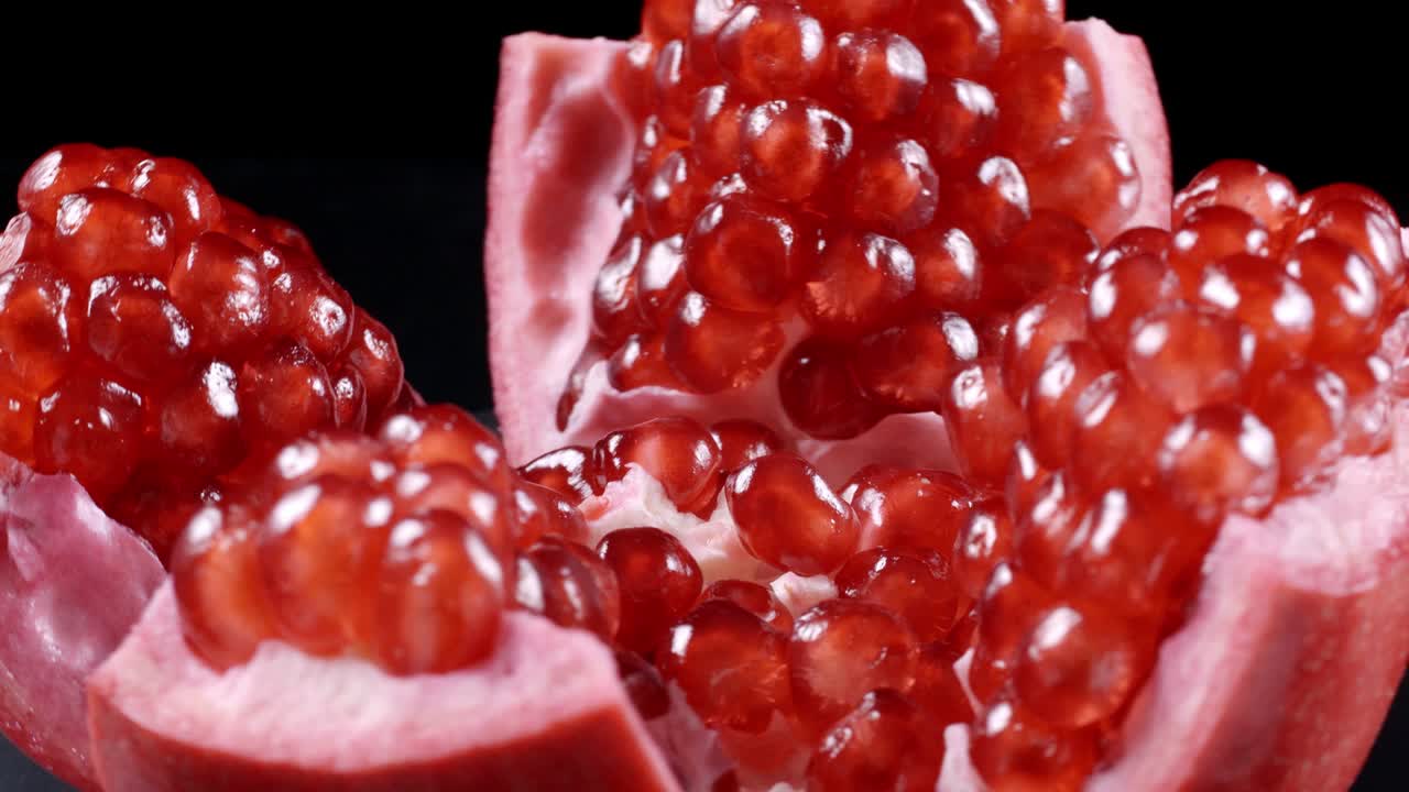 Rotating red pomegranate seeds on black background