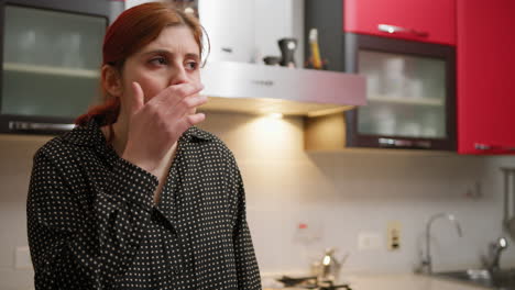 woman chews a biscuit and talks to her sister in the kitchen at home