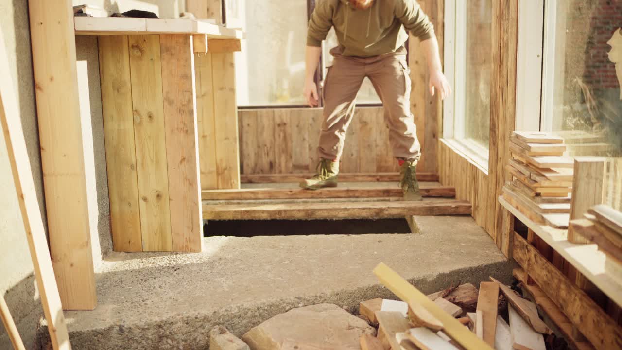 Uomo che copre il buco di cemento con assi di legno