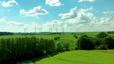 Ausgedehnte-Grüne-Felder-Mit-Windrädern-Und-Bäumen-Unter-Einem-Blauen-Himmel-Mit-Wolken