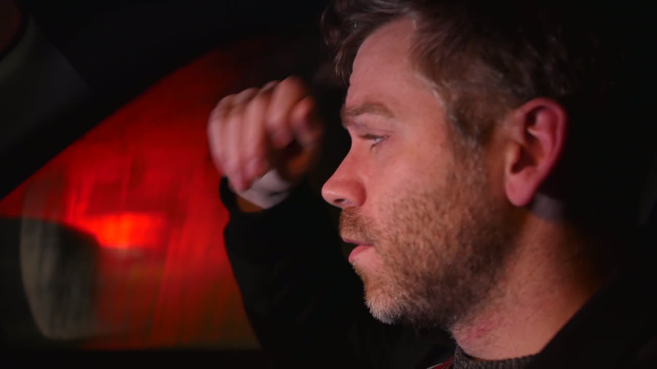 바쁜 도로를 지나가는 교통 체증으로 밤에 차 안에 혼자 있는 슬픈 남자