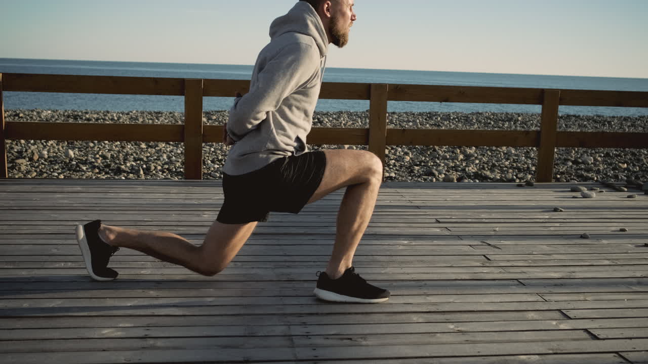 Uomo che fa affondi su una passeggiata lungomare