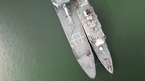 overhead zoom out aerial view of a couple of ships abandoned in the water