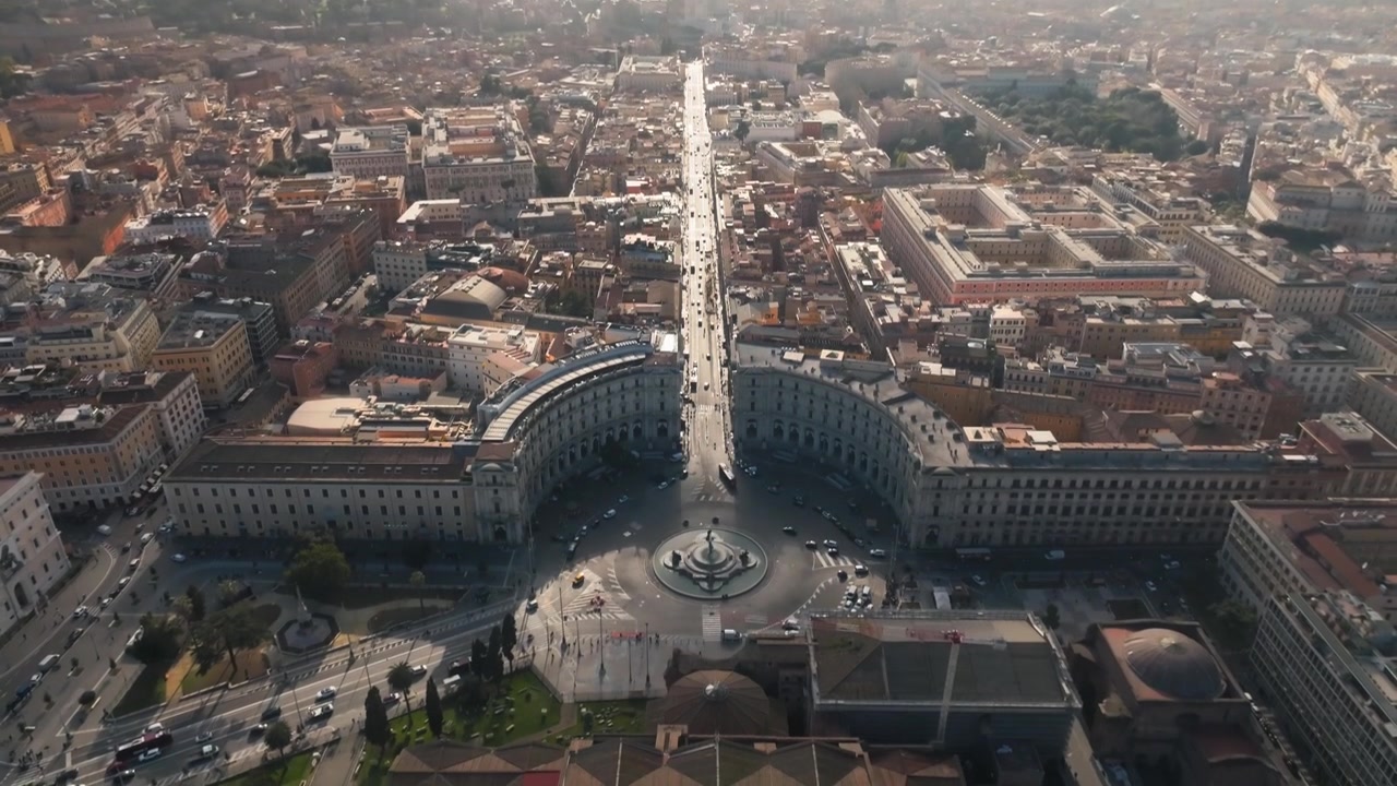 Ripresa aerea con drone che sorvola Piazza della Repubblica a Roma, mostrando il traffico di Via Nazionale e le antiche Terme di Diocleziano con lo storico cortile del chiostro