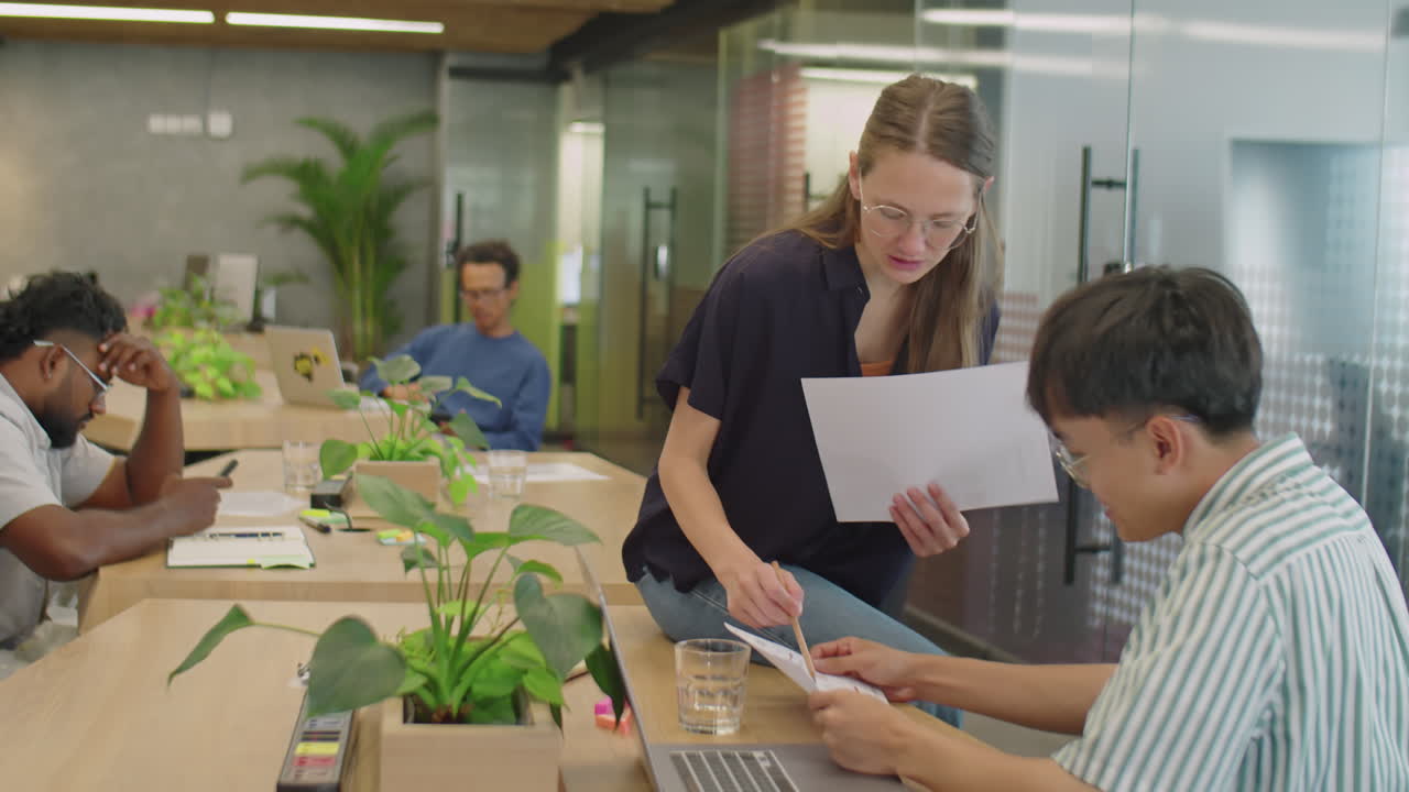 Young Colleagues Discussing Documents in Coworking Room