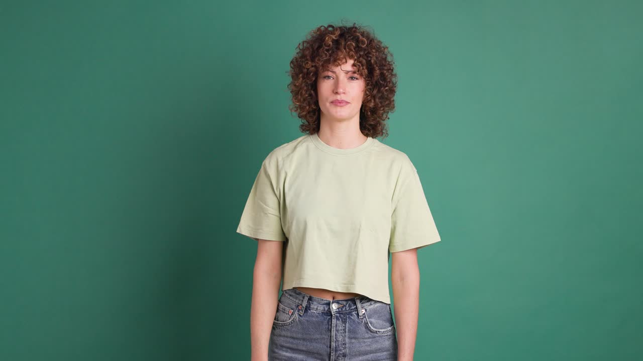 Adult woman with curly hair looking unhappy showing thumbs down gesture