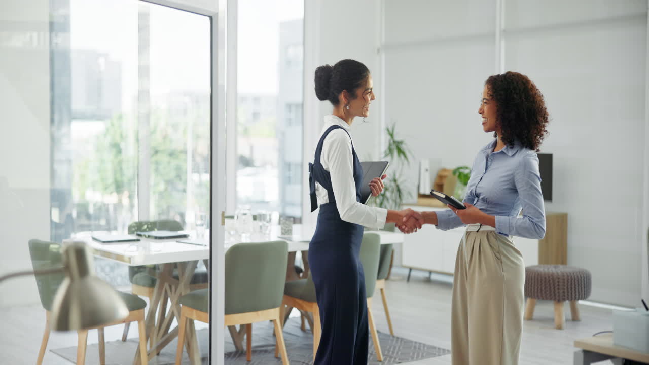 dos mujeres de negocios estrechando la mano en una oficina moderna