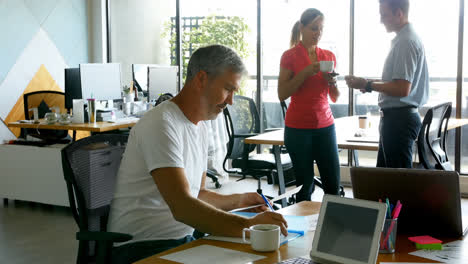 executive working on desk while his colleagues talking in background 4k